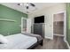 Bedroom with green accent wall, ceiling fan, luxury vinyl plank flooring, and flat screen TV at 15322 W Montecito Ave, Goodyear, AZ 85395