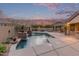 Backyard featuring a pool, outdoor kitchen, patio, and mature landscaping at sunset at 15881 W Berkeley Rd, Goodyear, AZ 85395