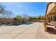 Backyard pool area featuring an outdoor kitchen, patio area, lush landscaping, and block wall fencing at 15881 W Berkeley Rd, Goodyear, AZ 85395