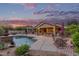 Backyard featuring a pool, outdoor kitchen, patio, and mature landscaping at sunset at 15881 W Berkeley Rd, Goodyear, AZ 85395