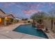 Inviting backyard pool with lush landscaping, a covered patio, and a built-in outdoor kitchen at 15881 W Berkeley Rd, Goodyear, AZ 85395