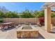 Outdoor living area with stone fire pit, iron table and chairs, and mature landscaping at 15881 W Berkeley Rd, Goodyear, AZ 85395