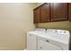 Laundry room with white washer, dryer, and dark wooden cabinets at 15881 W Berkeley Rd, Goodyear, AZ 85395