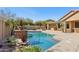 Backyard pool with stone water feature, outdoor kitchen, covered patio, and fire pit at 15881 W Berkeley Rd, Goodyear, AZ 85395