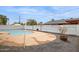 A backyard pool with concrete and gray gravel surrounding a white block fence and clear blue sky at 1747 W Belfast St, Mesa, AZ 85201