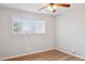 Bright bedroom with wood-look floors, a ceiling fan, and a window offering natural light at 1747 W Belfast St, Mesa, AZ 85201