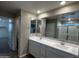 Bathroom with a double sink vanity, large mirror and a view to the shower and commode at 17558 W Lupine Ave, Goodyear, AZ 85338