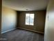 Bedroom featuring neutral carpet, walls, and a window with neighborhood views at 17558 W Lupine Ave, Goodyear, AZ 85338