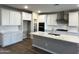 Modern kitchen features white cabinets, quartz countertops, stainless steel appliances, and an island with a sink at 17558 W Lupine Ave, Goodyear, AZ 85338