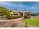 Attractive home exterior with putting green, mature trees, and a covered patio at 17642 N Ironhorse Dr, Surprise, AZ 85374