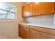 Well-lit laundry room featuring wood cabinets, white countertop and window view at 17642 N Ironhorse Dr, Surprise, AZ 85374