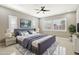 Well-lit bedroom with a ceiling fan, a large bed, and windows with plantation shutters at 1800 N 156Th Dr, Goodyear, AZ 85395