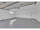 Clean garage featuring epoxy flooring, white walls, a window and an automatic door system at 18402 N 94Th Dr, Sun City, AZ 85373