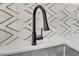 Close-up of kitchen sink with matte black faucet and striking geometric backsplash at 18402 N 94Th Dr, Sun City, AZ 85373