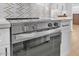 Close-up of new stainless steel stove with white cabinets and marble backsplash at 18402 N 94Th Dr, Sun City, AZ 85373