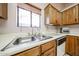 A close up of a stainless steel sink with wood cabinets, white countertops, and a window at 18660 N 71St Ln, Glendale, AZ 85308