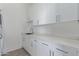 Well-lit laundry room with white cabinets and countertops, stainless steel faucet and plenty of counter space at 2940 E South Mountain Ave, Phoenix, AZ 85042