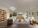 Bright living room featuring modern furniture, neutral walls, ceiling fan, and ample natural light from the arched windows at 42618 W Oakland Dr, Maricopa, AZ 85138