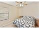 This carpeted bedroom features a window, ceiling fan, and neutral decor at 43870 W Baker Dr, Maricopa, AZ 85138