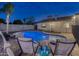 Relaxing backyard featuring a pool, stone patio, lounge chairs, and covered patio at dusk at 4826 W Michigan Ave, Glendale, AZ 85308