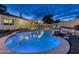 Backyard with a sparkling pool, stone patio, and cozy seating area under a covered patio at twilight at 4826 W Michigan Ave, Glendale, AZ 85308