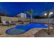 Outdoor pool with a rock waterfall, stone patio, and a tropical palm tree at dusk at 4826 W Michigan Ave, Glendale, AZ 85308