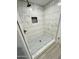 A modern shower with white marble-patterned tile and a mosaic tile floor at 8139 W Columbine Dr, Peoria, AZ 85381