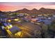 Aerial view of a sprawling ranch property featuring a horse training area, barn, and mountain views at 9331 E Mclellan Rd, Mesa, AZ 85207