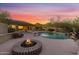 Spacious backyard featuring a fire pit, pool, desert landscape, and solar panels on the roof at 9331 E Mclellan Rd, Mesa, AZ 85207