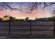 Fenced horse arena at sunset, with trees, barn and another building in the background at 9331 E Mclellan Rd, Mesa, AZ 85207