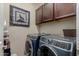 Laundry room showcasing modern washer and dryer units with overhead cabinet storage at 11023 E Shepperd Ave, Mesa, AZ 85212