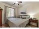 Cozy bedroom features ceiling fan, large window, comfortable bed, and nightstand with reading lamp at 1209 E Park Ave, Chandler, AZ 85225