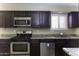 Kitchen featuring dark cabinets, stainless steel appliances, granite counters, and window with blinds at 1518 N Gilbert Ave, Casa Grande, AZ 85122