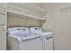 Functional laundry room featuring a washing machine and dryer, shelving, and tiled floors at 17062 N 184Th Dr, Surprise, AZ 85374
