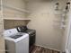 Functional laundry room equipped with washer, dryer, wire shelving and hanging rack for convenient storage and organization at 17062 N 184Th Dr, Surprise, AZ 85374