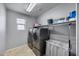 Bright laundry room equipped with washer, dryer, shelving, overhead lighting, and tile floor at 17916 N 183Rd Ave, Surprise, AZ 85374