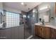 Modern bathroom featuring a glass block window, sleek walk-in shower, and floating vanity with a marble countertop at 19277 N 78Th Ln, Glendale, AZ 85308