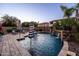 Beautiful backyard pool with a stone waterfall feature, lush landscaping, and an umbrella, creating a serene backyard oasis at 21030 E Misty Ln, Queen Creek, AZ 85142