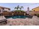 Sparkling backyard pool with a stone waterfall feature, lush landscaping, and ample patio space with a partially shaded umbrella at 21030 E Misty Ln, Queen Creek, AZ 85142