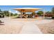 Community playground featuring a covered play structure, climbing wall, swings, and a surrounding paved pathway at 21030 E Misty Ln, Queen Creek, AZ 85142