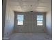 Bright living room showcases fresh drywall and two windows with views of the desert landscape at 24090 W Sunland Ave, Buckeye, AZ 85326
