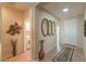 Hallway featuring neutral walls, tile floors, decorative art, and access to laundry area and front door at 2480 E Hancock Trl, Casa Grande, AZ 85194