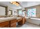 Beautiful bathroom featuring double sinks, a tub, stylish mirrors, and glass block window at 29437 W Columbus Ave, Buckeye, AZ 85396