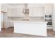 Gorgeous white kitchen with stainless steel appliances, tile backsplash, and a large center island with white countertops at 352 E Las Perlas Ln, San Tan Valley, AZ 85140