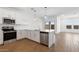 Well-lit kitchen featuring stainless appliances, white cabinets, quartz counters, wood flooring and backyard view at 3937 S 233Rd Ln, Buckeye, AZ 85326