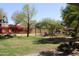 Lush backyard oasis with mature trees, vibrant bougainvillea, and a charming pergola at 3957 N 148Th Dr, Goodyear, AZ 85395