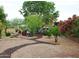 Large back yard with gravel, mature trees, pavers, outdoor seating, and blooming flowers at 3957 N 148Th Dr, Goodyear, AZ 85395