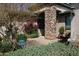 Inviting front porch with a stone pillar, colorful bougainvillea, green shrubs, and a lantern for ambient lighting at 3957 N 148Th Dr, Goodyear, AZ 85395