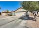 Exterior view of the home with a two-car garage, desert landscaping, and mature trees at 4332 W Carson Rd, Laveen, AZ 85339