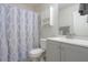 Bright bathroom with a white vanity, shower featuring a blue decorative shower curtain, and plenty of storage at 43409 W Sagebrush Trl, Maricopa, AZ 85138